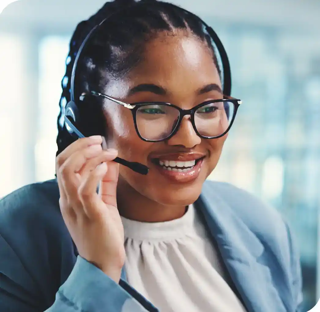 Smiling female BPO agent wearing glasses and a headset adjusting her microphone in an office