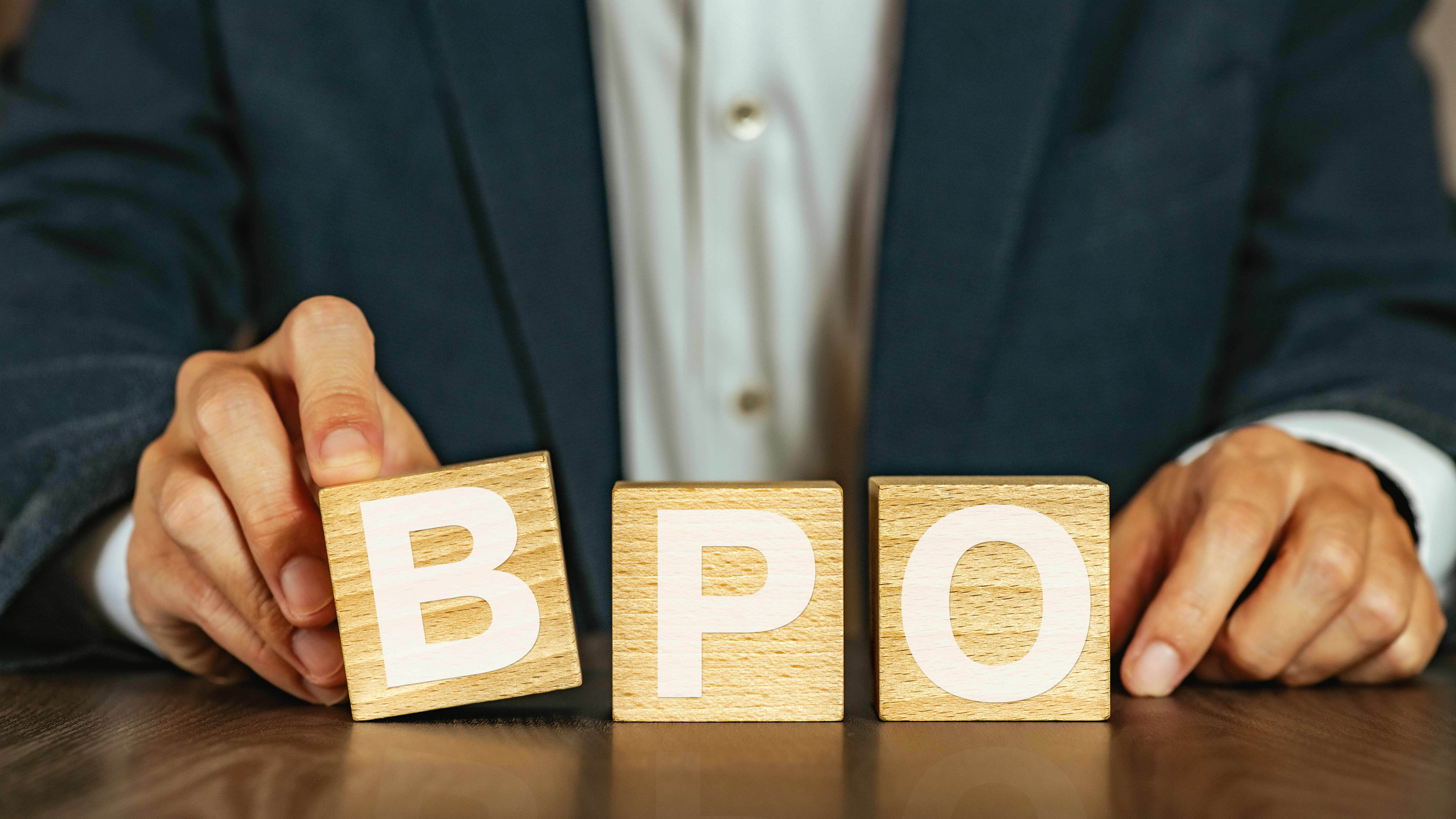 Business professional holding wooden blocks spelling BPO
